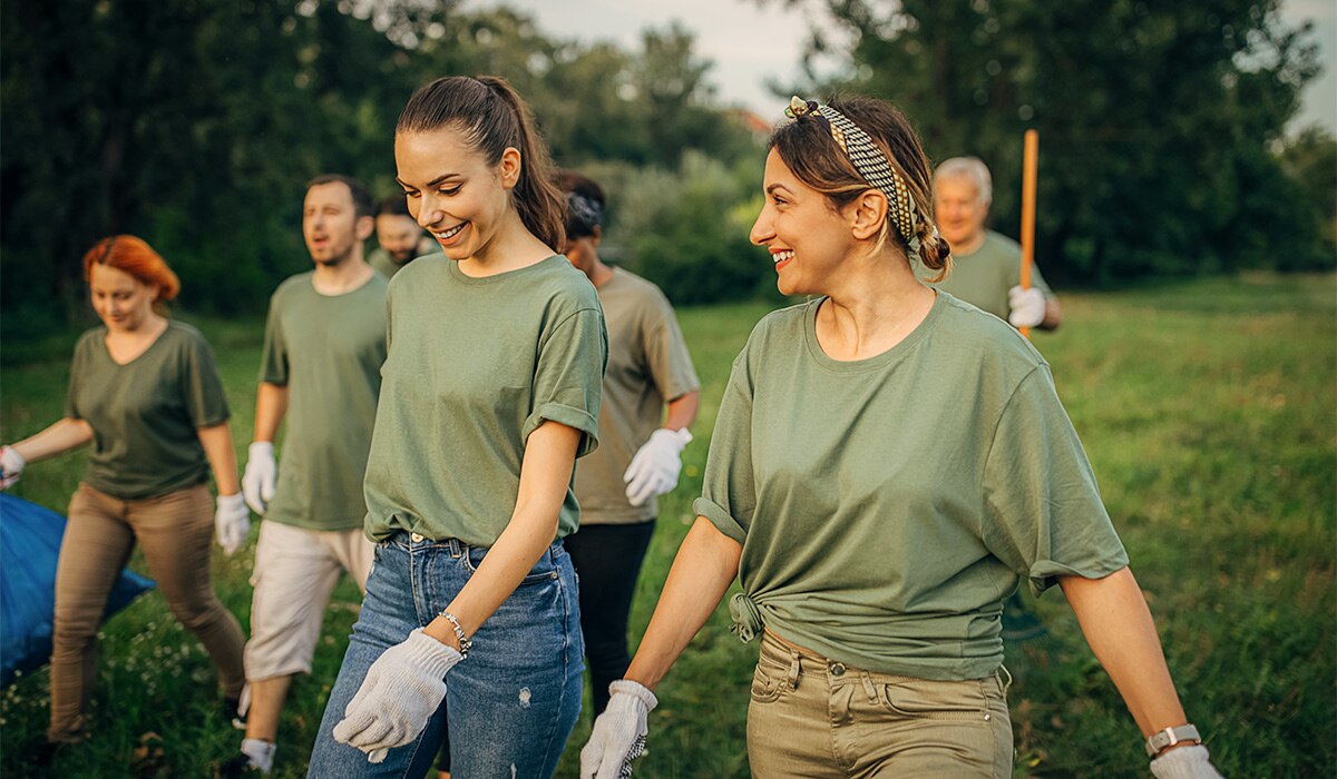 Volunteers outdoors wearing work shirts and gloves.